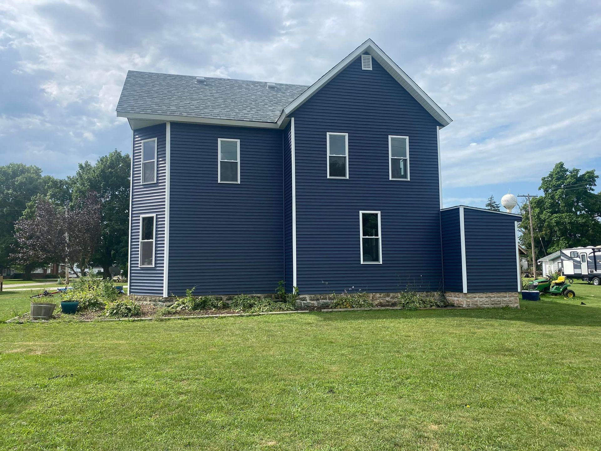 A large blue house is sitting on top of a lush green field.
