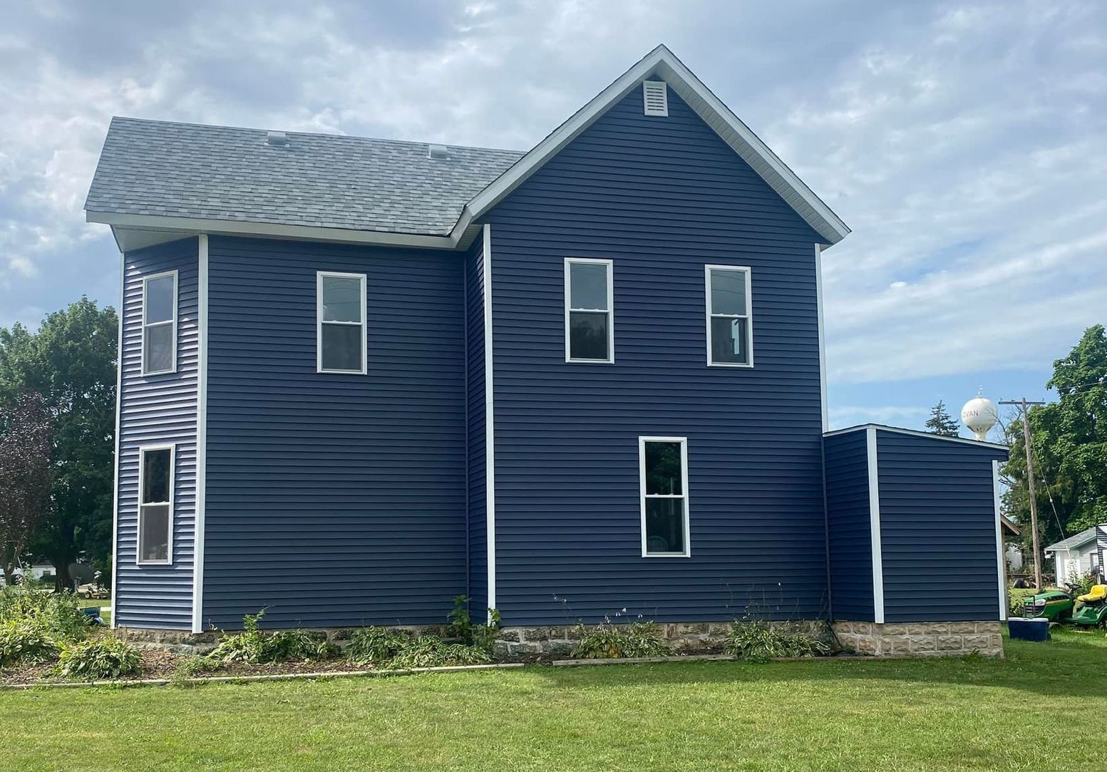 A white house with a gutter on the side of it and a blue sky in the background.