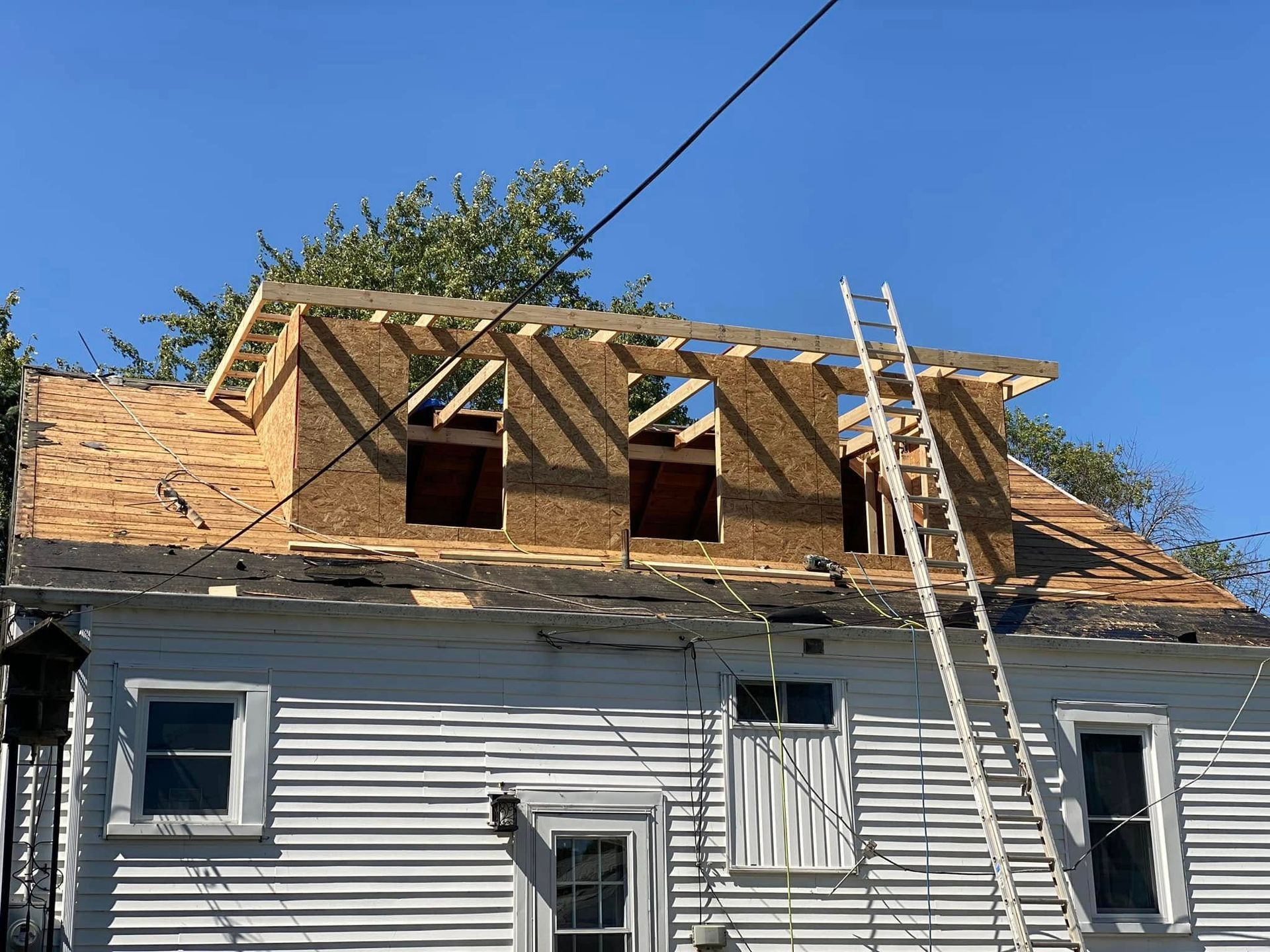 A white house with a wooden roof under construction.