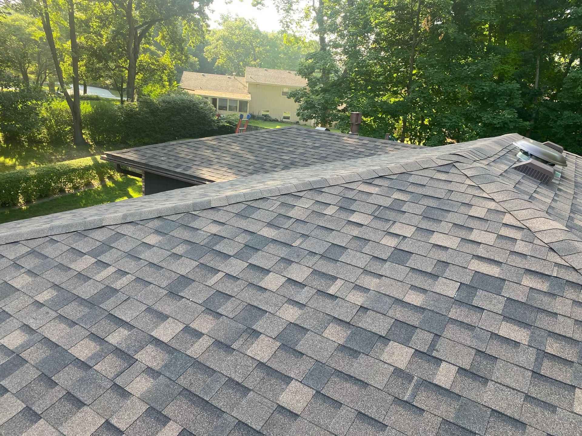 A roof with a lot of shingles on it and a house in the background.