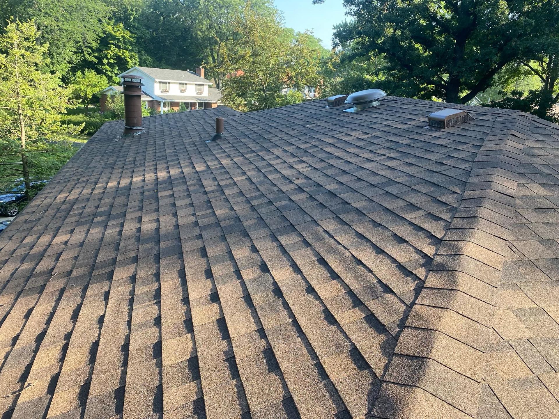 A close up of a roof with a house in the background.