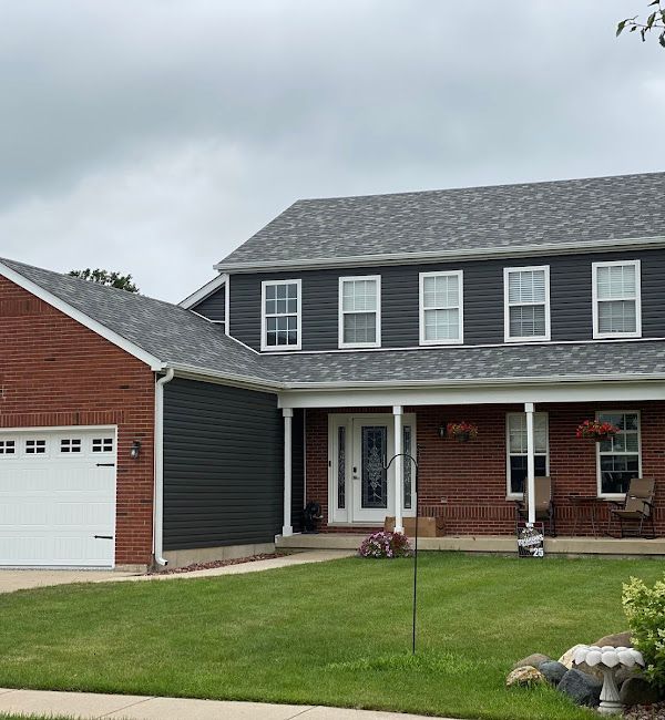 A brick house with a black siding and a white garage door
