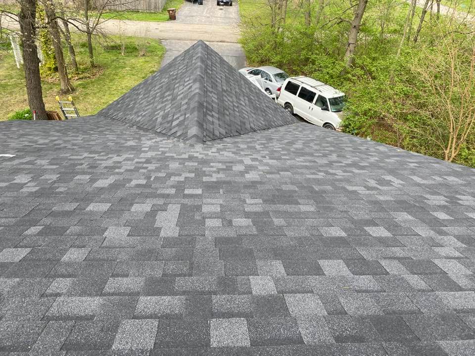 The roof of a house with a pyramid shaped roof and a white van parked on the side of the road.
