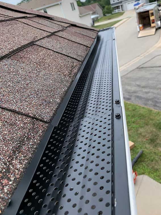 A yellow leaf is sticking out of a gutter on a roof.