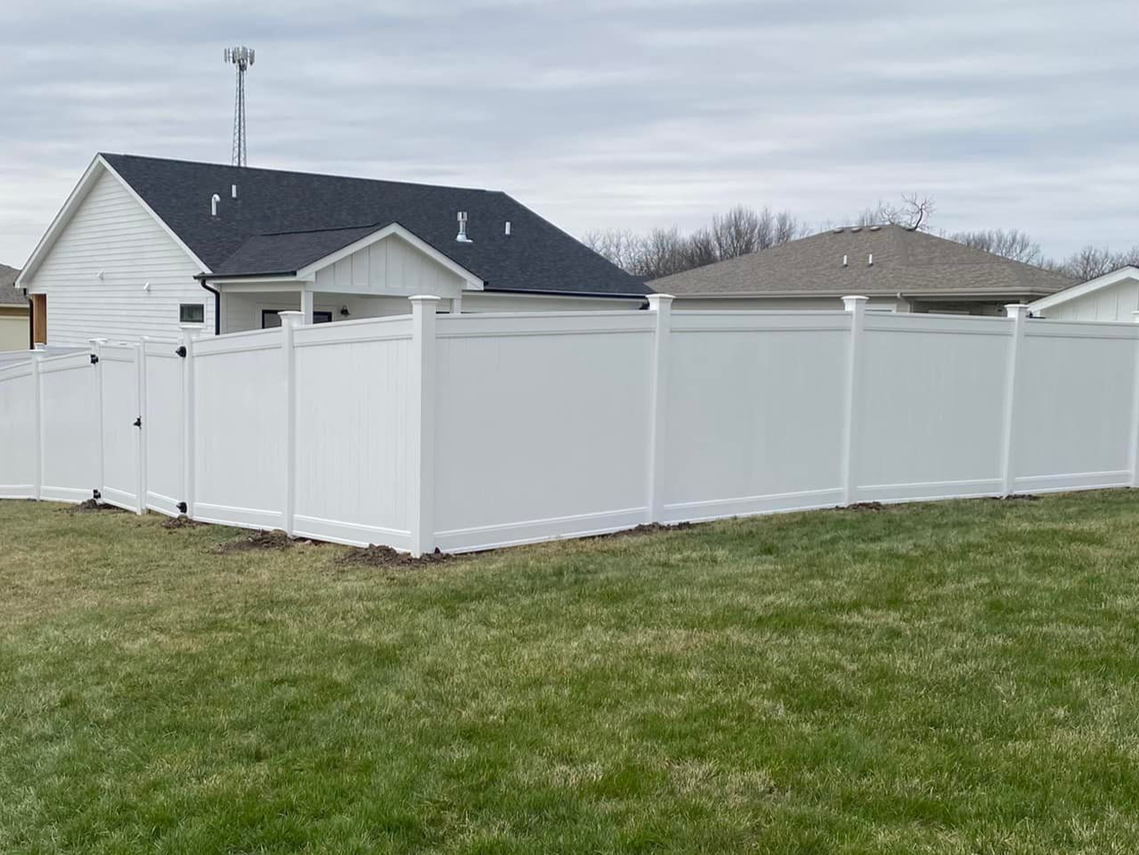 White vinyl privacy fence surrounding a backyard beside a house on a grassy lot