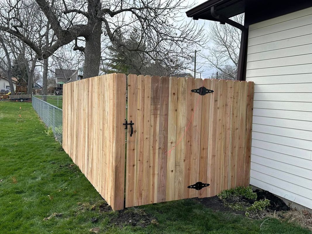 Wooden fence enclosure beside a white house in a grassy yard