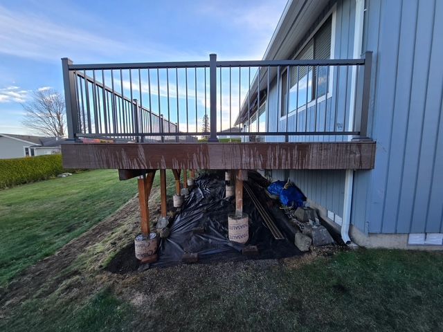 Raised deck with temporary support posts and jacks beside a house, seen from the side.