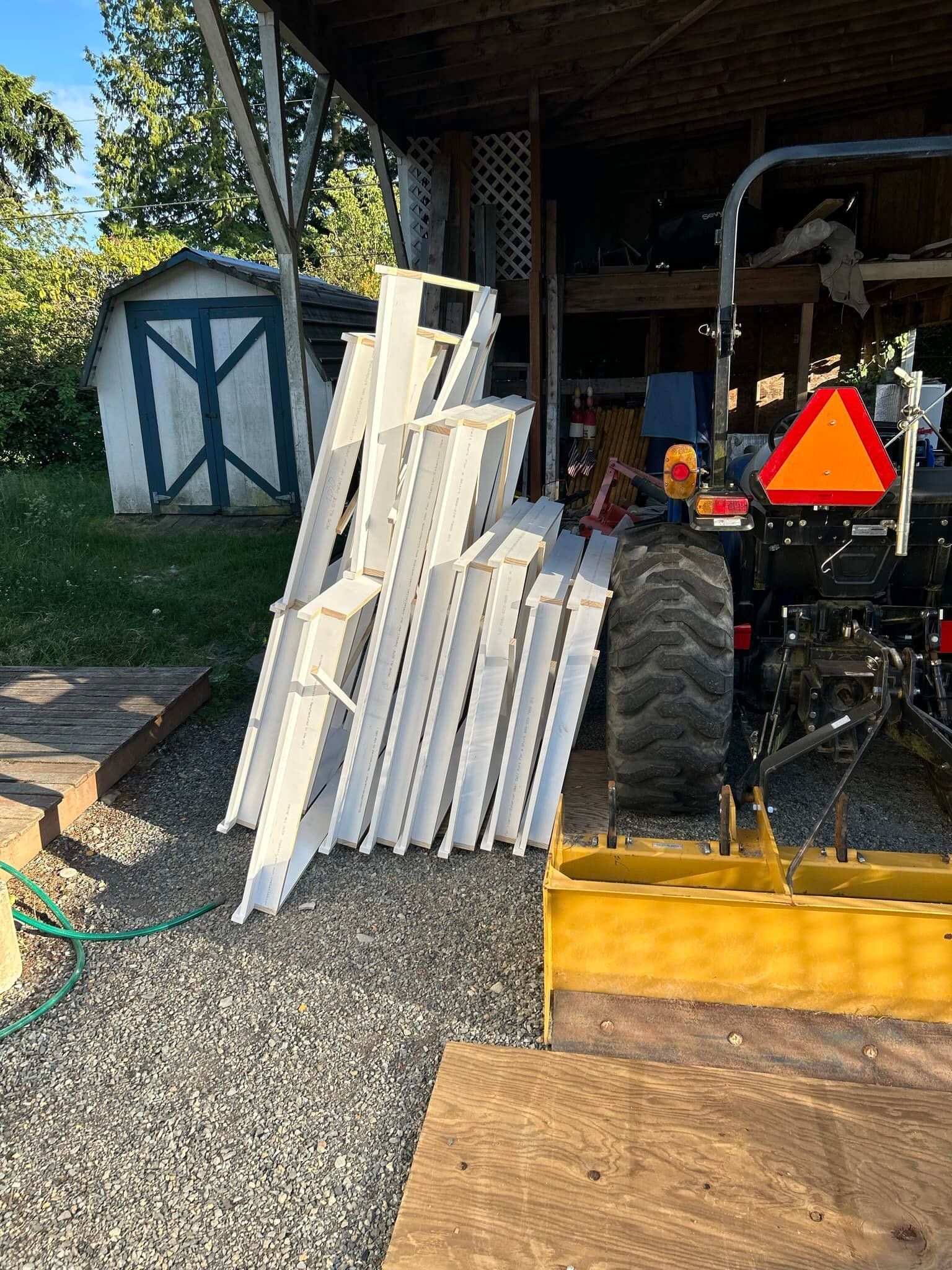 White boards stacked in a shed beside a tractor with a slow-moving vehicle sign.