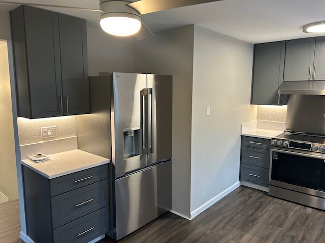 Modern gray kitchen with stainless steel appliances, dark cabinets, and a white wall divider