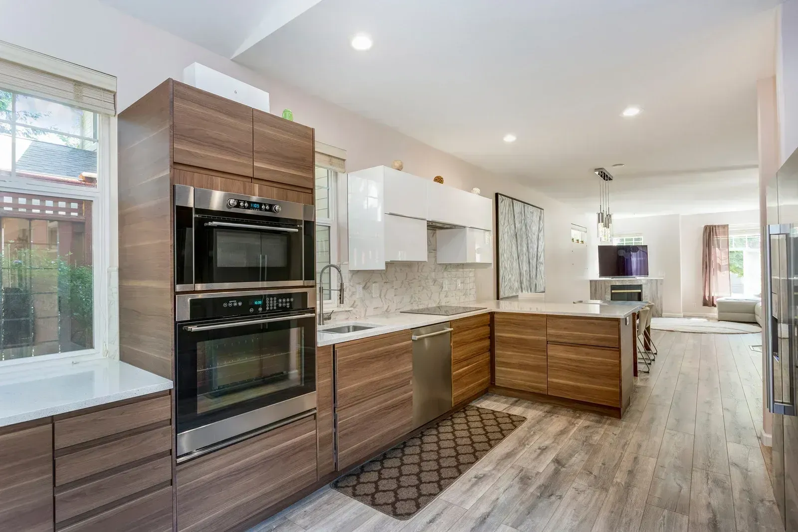 Modern kitchen with wood and white cabinets, stainless appliances, and a long island by a bright window