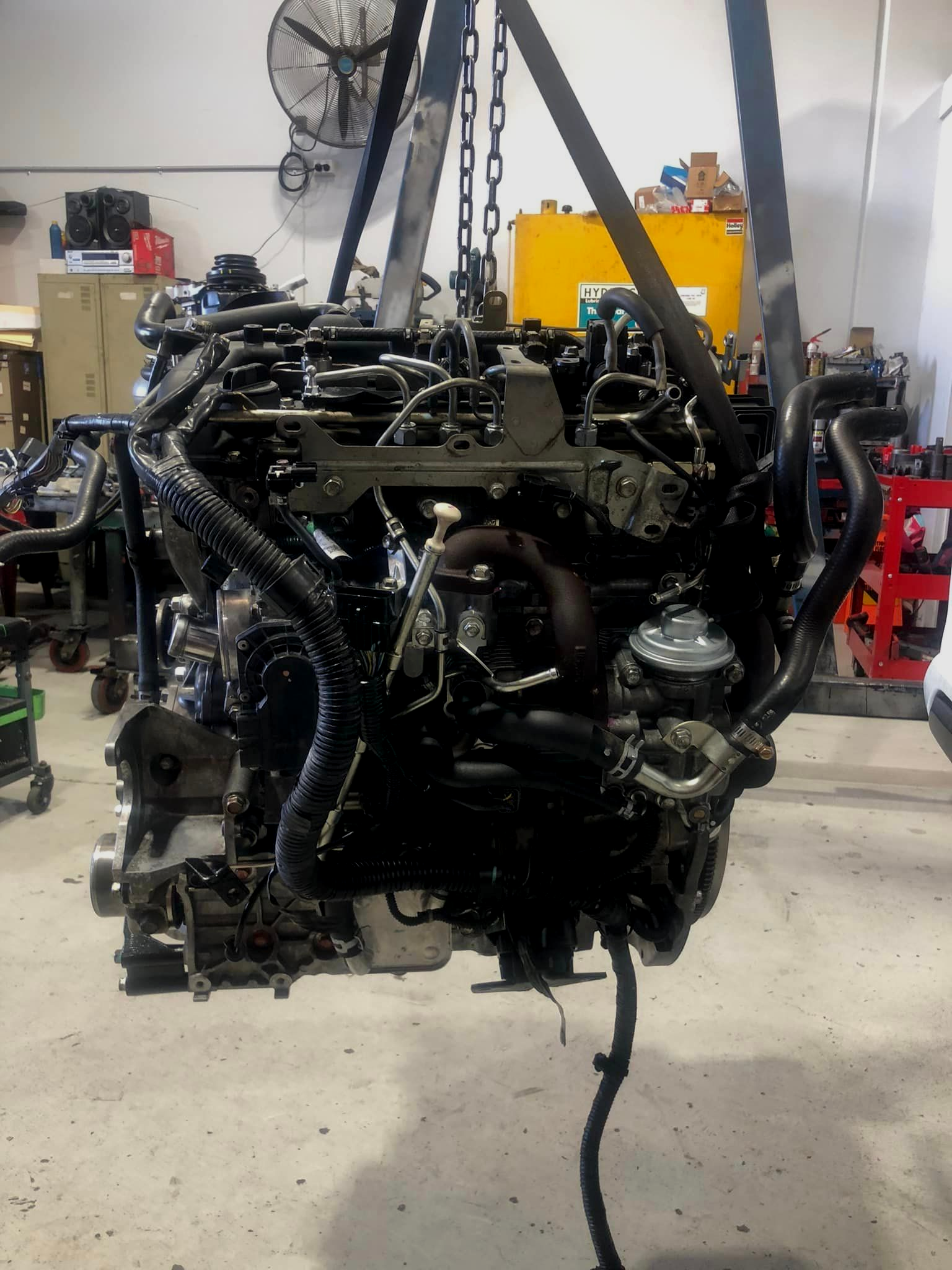 Engine suspended by a chain hoist in a workshop. — Experienced Mechanics on the Gold Coast, QLD