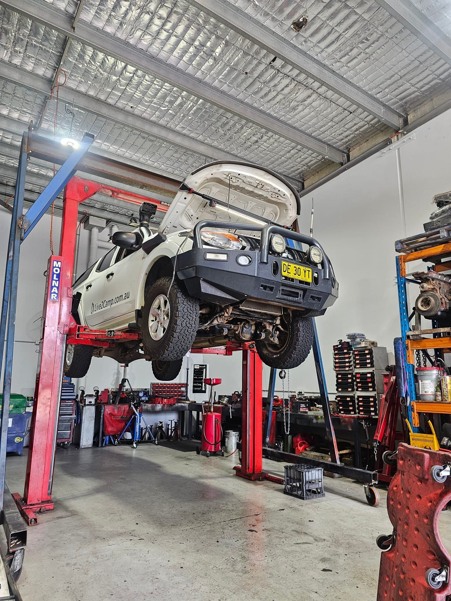 White Pickup Truck Raised on a Red Lift in a Garage, Hood Open — Diesel Engine Rebuilding Australia in Gold Coast, QLD