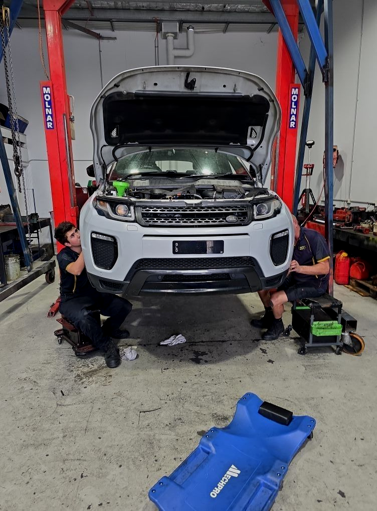 Two mechanics working on a white Land Rover on a lift in a garage. — Experienced Mechanics on the Gold Coast