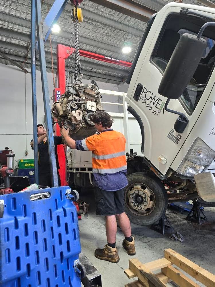 Two Mechanics Removing A Truck Engine Using A Hoist In A Workshop — Experienced Mechanics on the Gold Coast, QLD