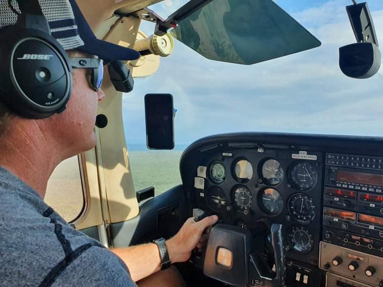A man wearing bose headphones is driving an airplane