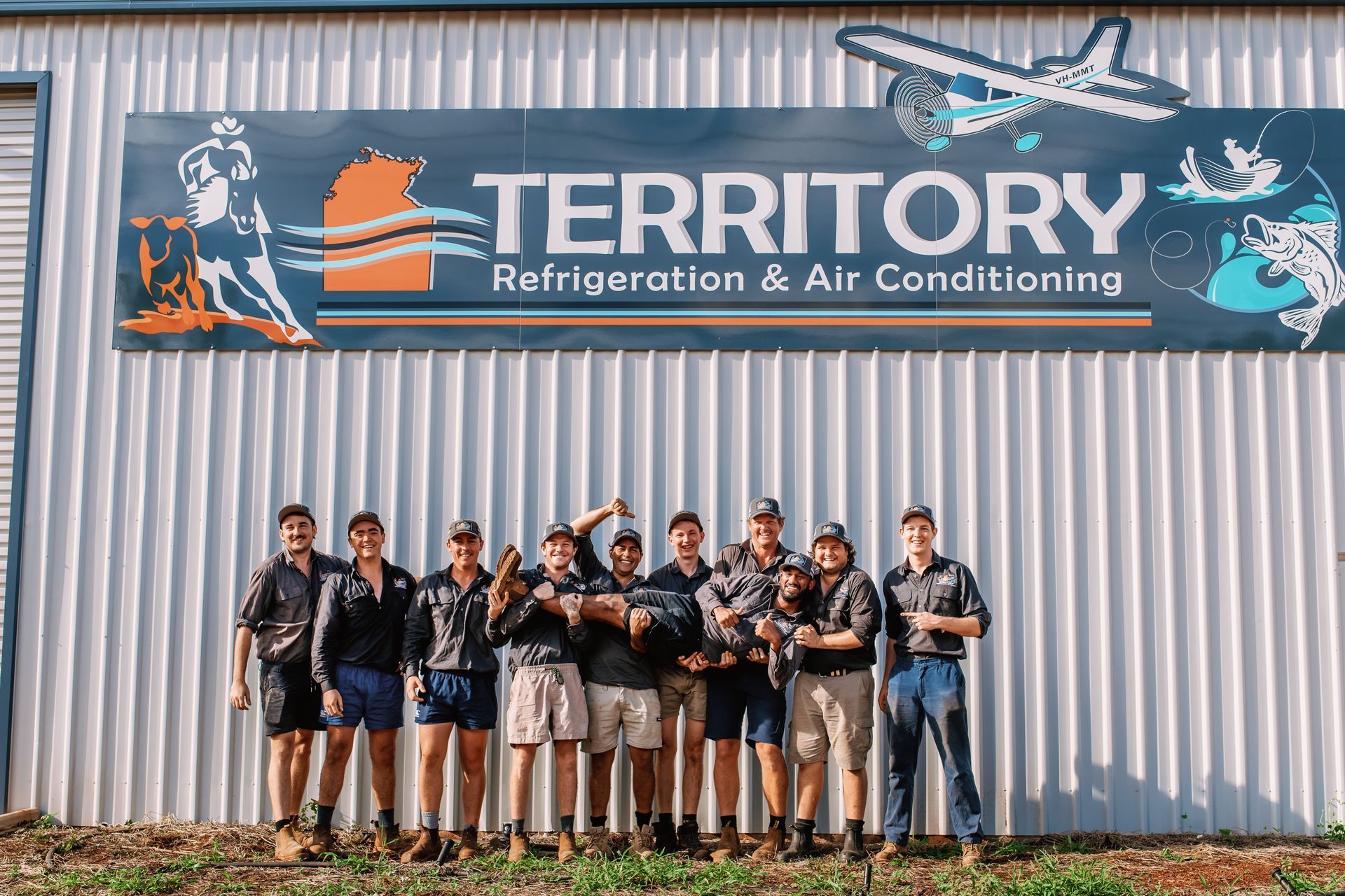 A Group of Men Are Posing for a Picture in Front of a Building — Refrigeration & Air Conditioning in Katherine East, NT