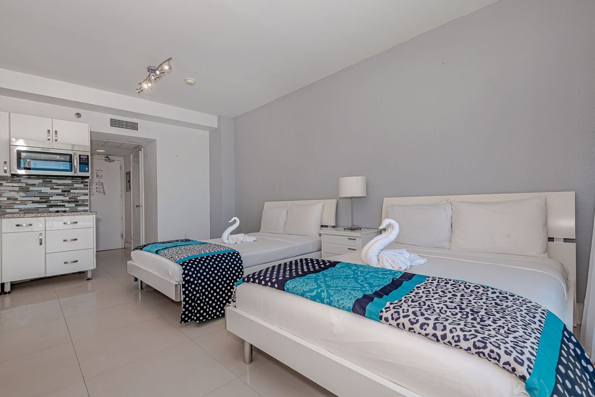 A hotel room with two beds and a kitchen.