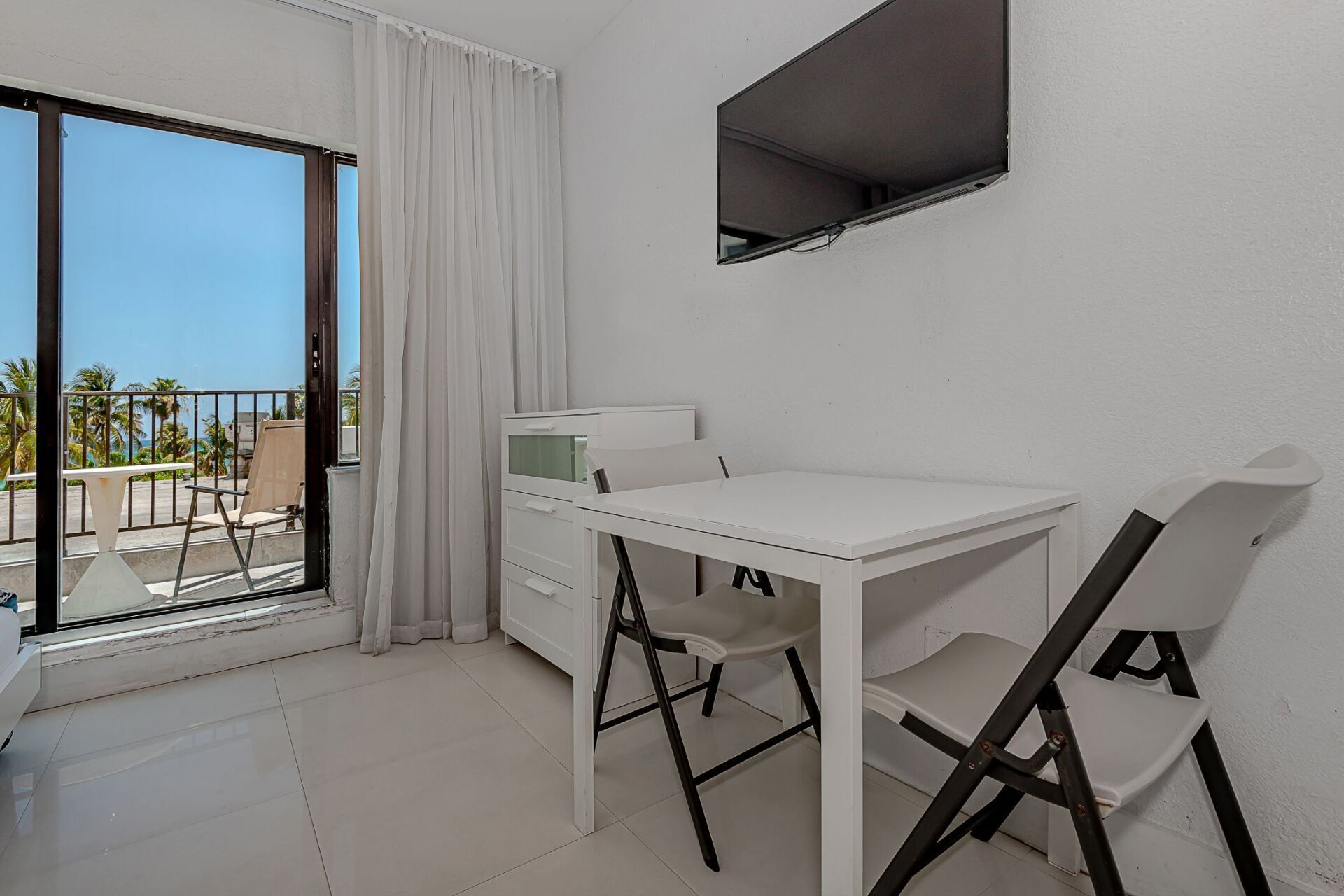 A white room with a table and chairs and a flat screen tv.