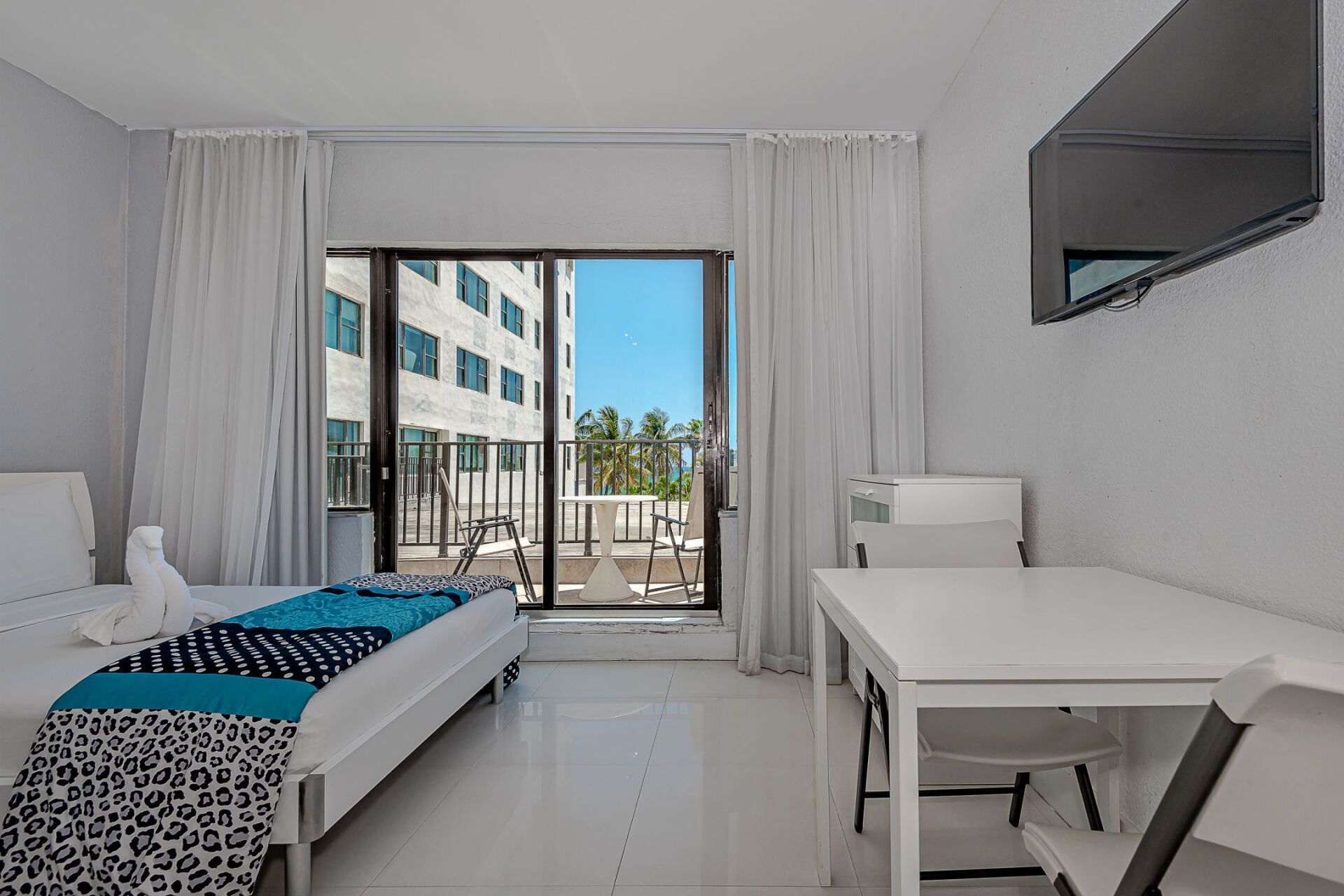 A hotel room with a bed , desk , chair and television.