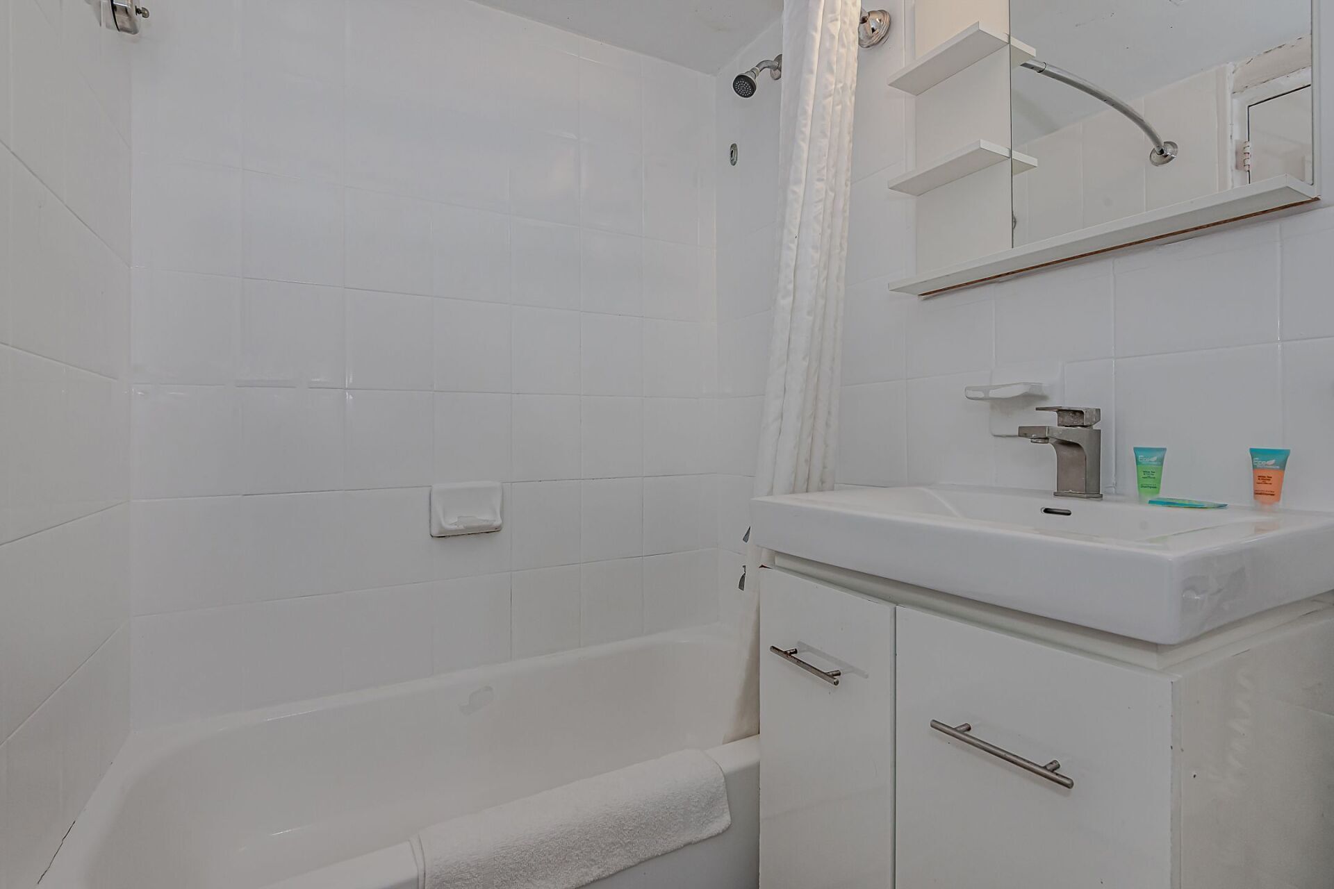 A bathroom with a sink , tub , shower and mirror.