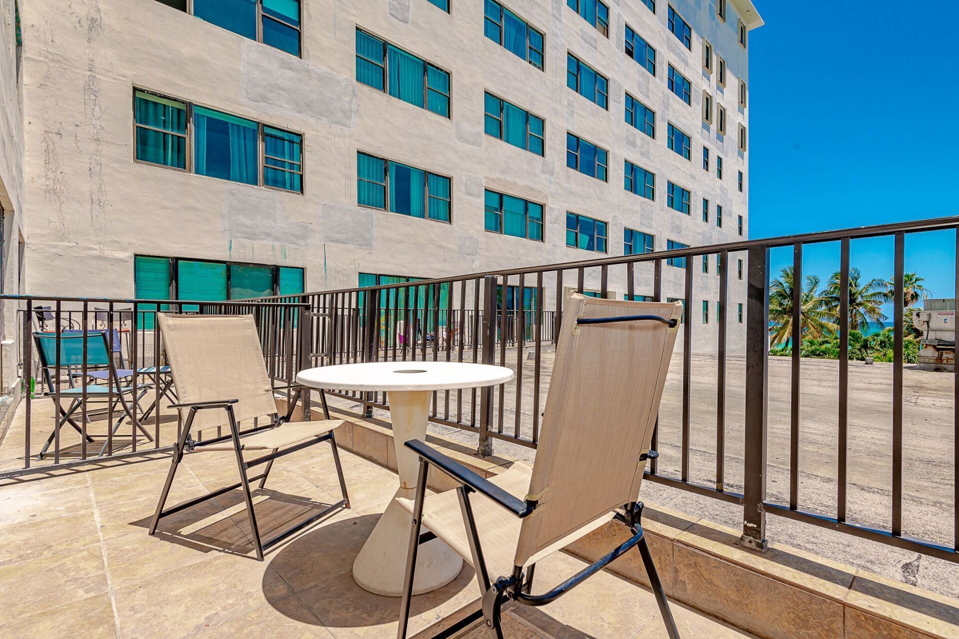 A balcony with a table and chairs in front of a large building.