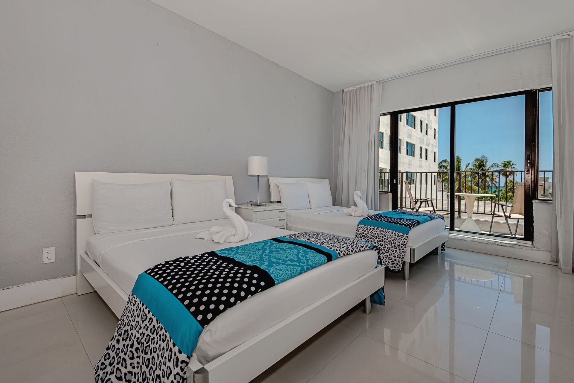 A hotel room with two beds and a balcony.