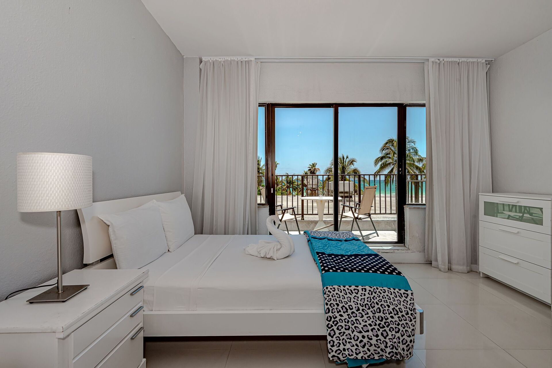 A bedroom with a large bed and a sliding glass door leading to a balcony.
