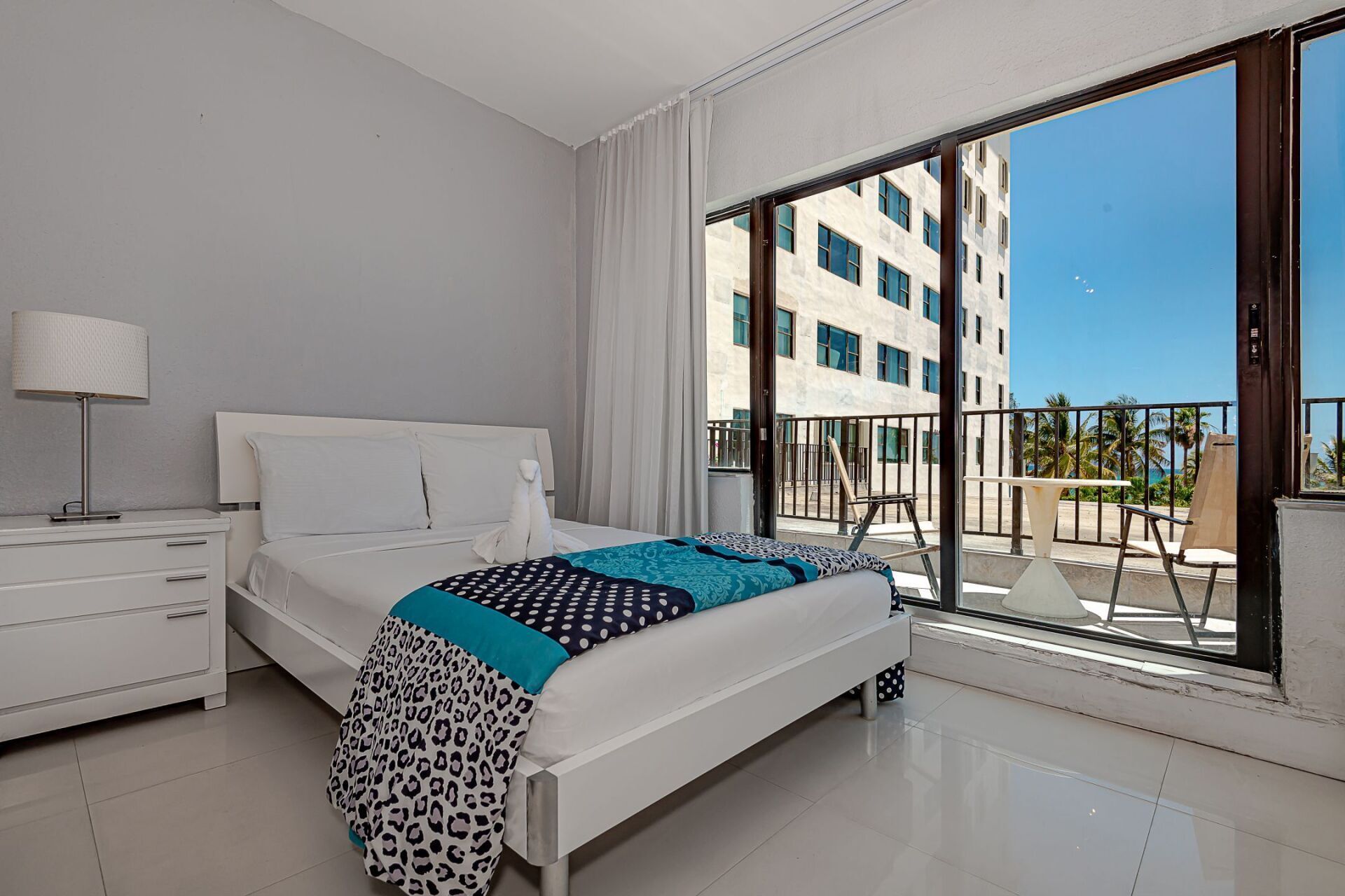 A bedroom with a large bed and a balcony with a view of the ocean.