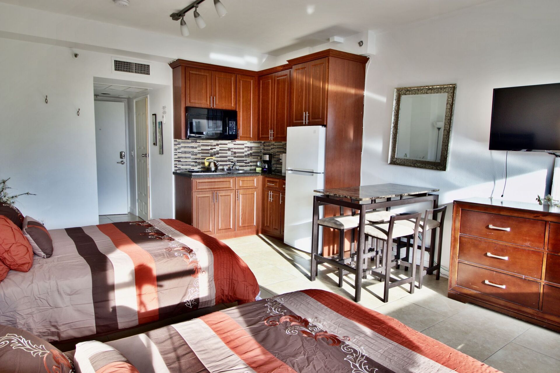 A bedroom with two beds a kitchen and a flat screen tv
