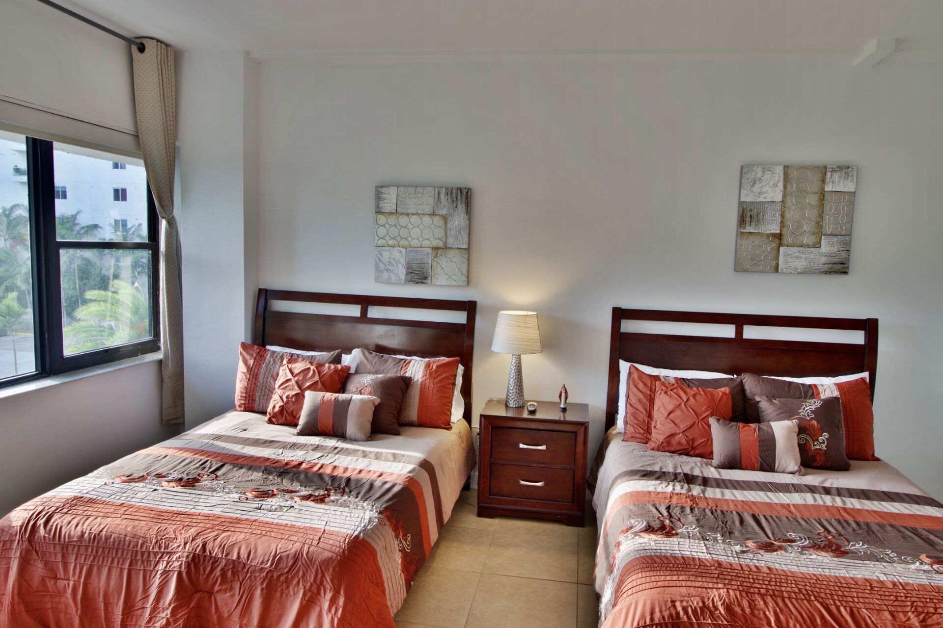 A bedroom with two beds and a nightstand