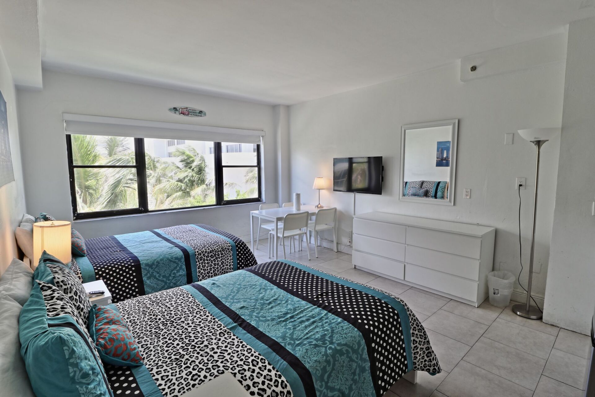A bedroom with two beds , a dresser , and a mirror.