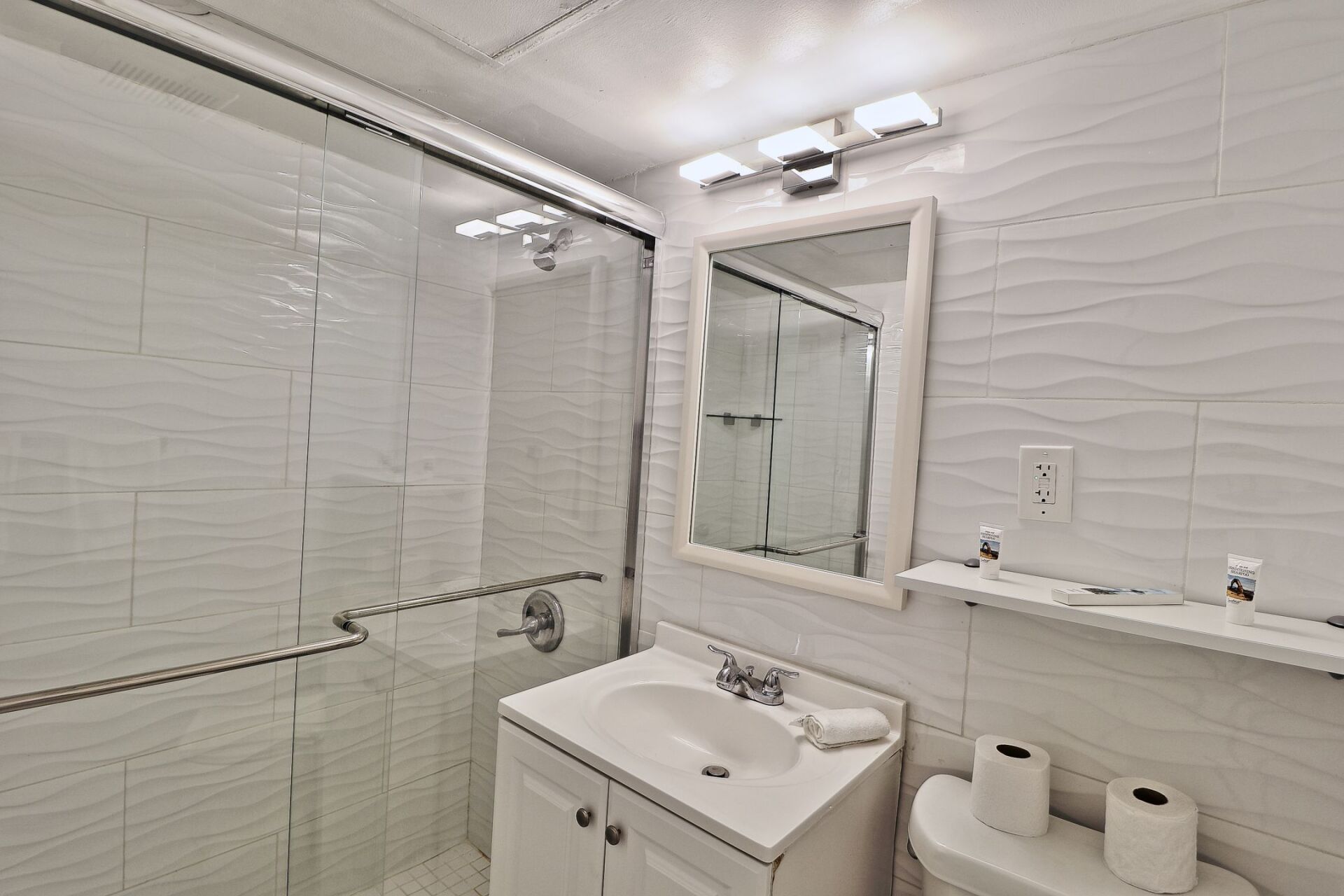 A bathroom with a sink , toilet , mirror and shower.