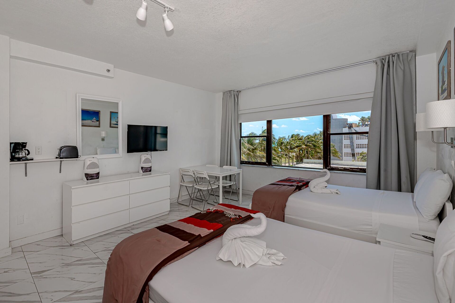 A hotel room with two beds , a dresser and a television.