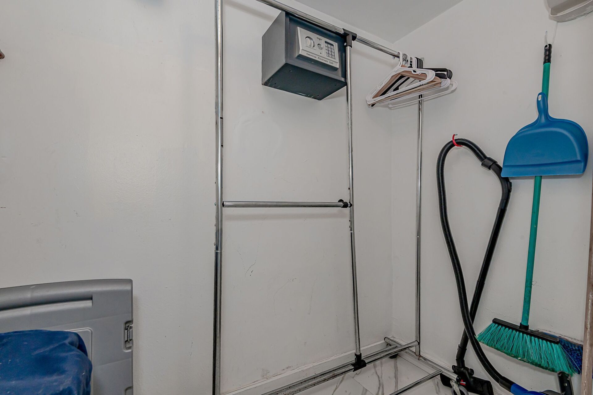 A closet with a vacuum cleaner , broom and clothes rack.