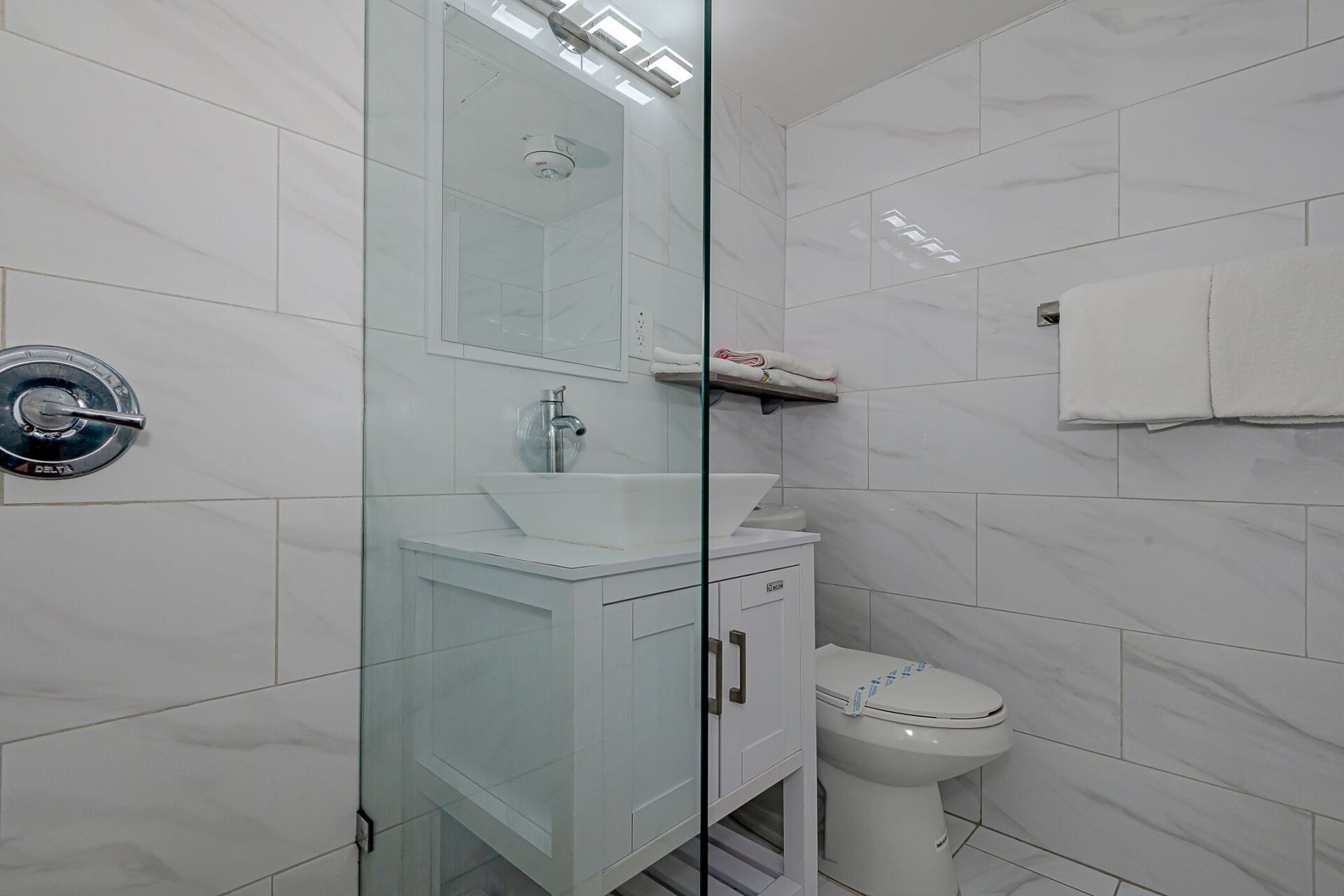 A bathroom with a toilet , sink and shower.