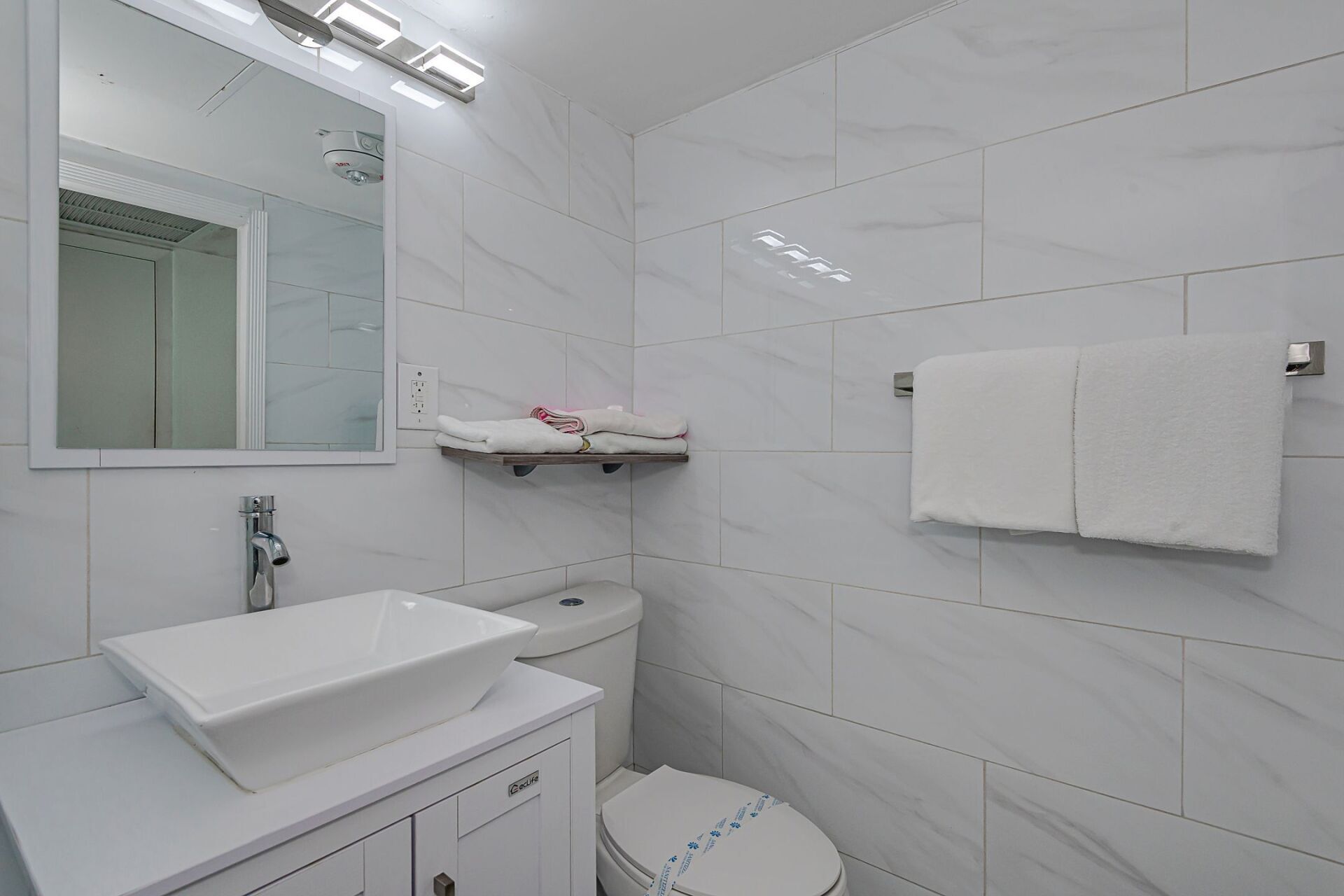 A bathroom with a sink , toilet and mirror.