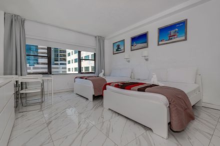 A bedroom with two beds , a desk and a window.