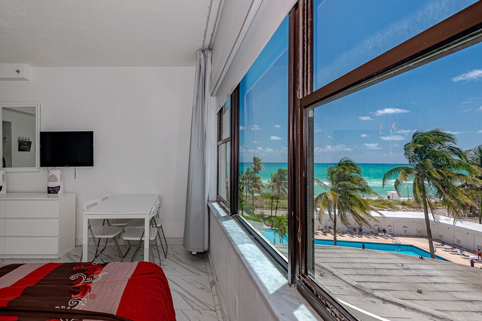 A bedroom with a large window looking out to the ocean.
