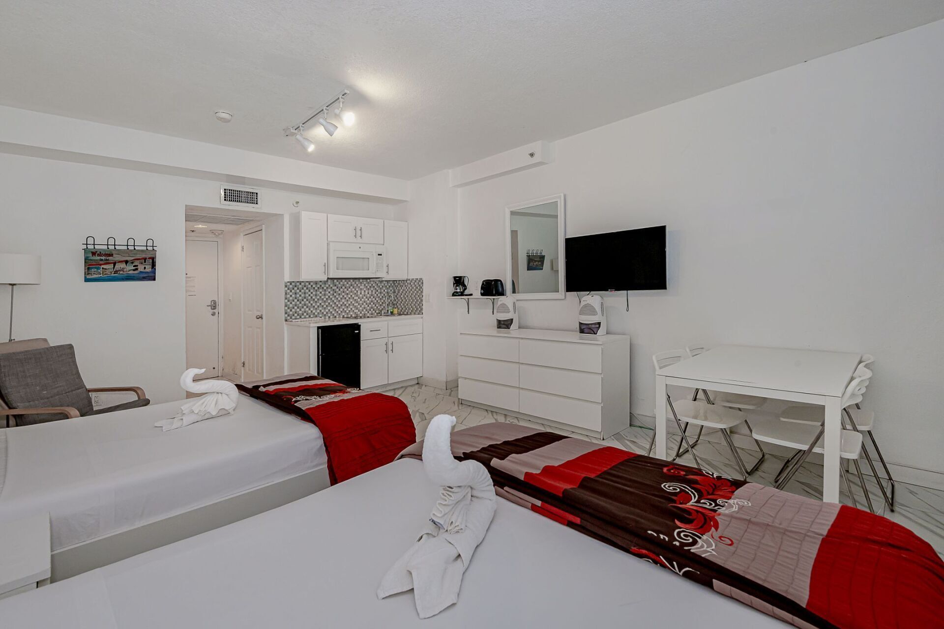 A hotel room with two beds , a table and a television.