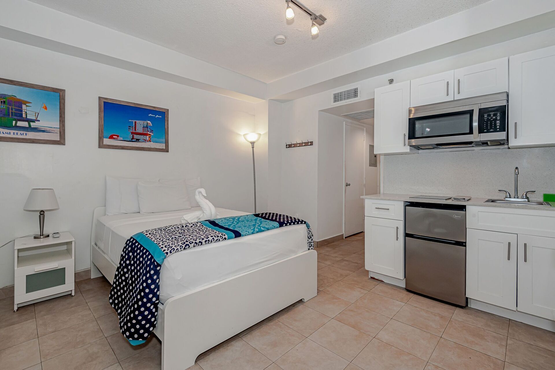 A bedroom with a bed and a kitchen with stainless steel appliances