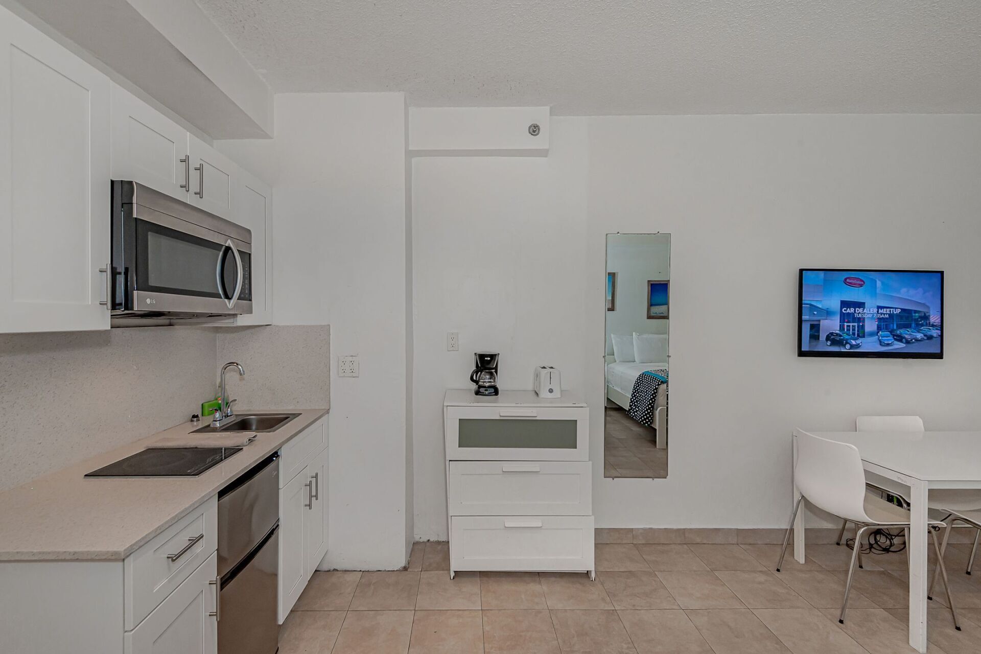 A kitchen with a table and chairs and a television on the wall.