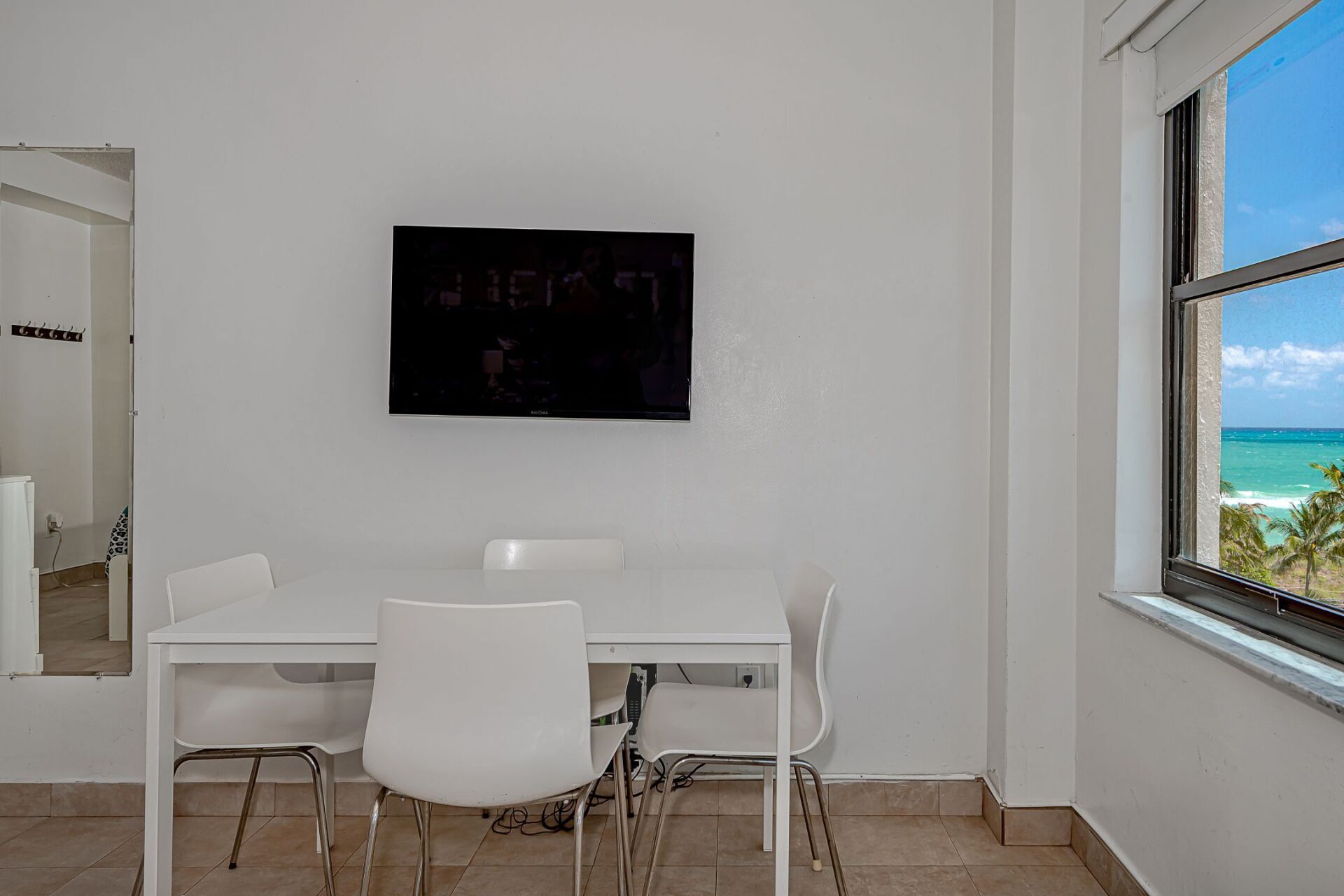 There is a table and chairs in the room with a television on the wall.