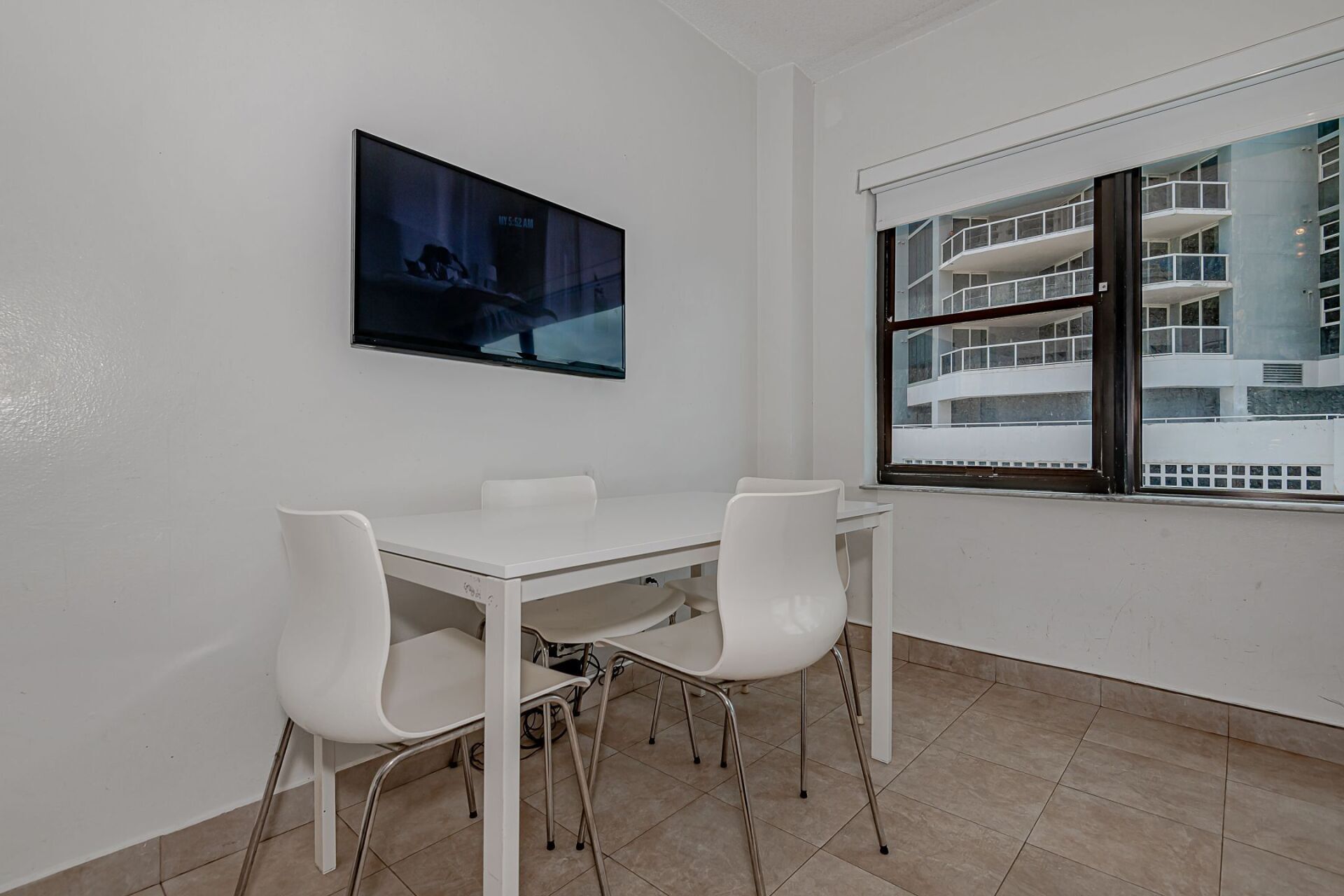 A dining room with a table and chairs and a flat screen tv on the wall.