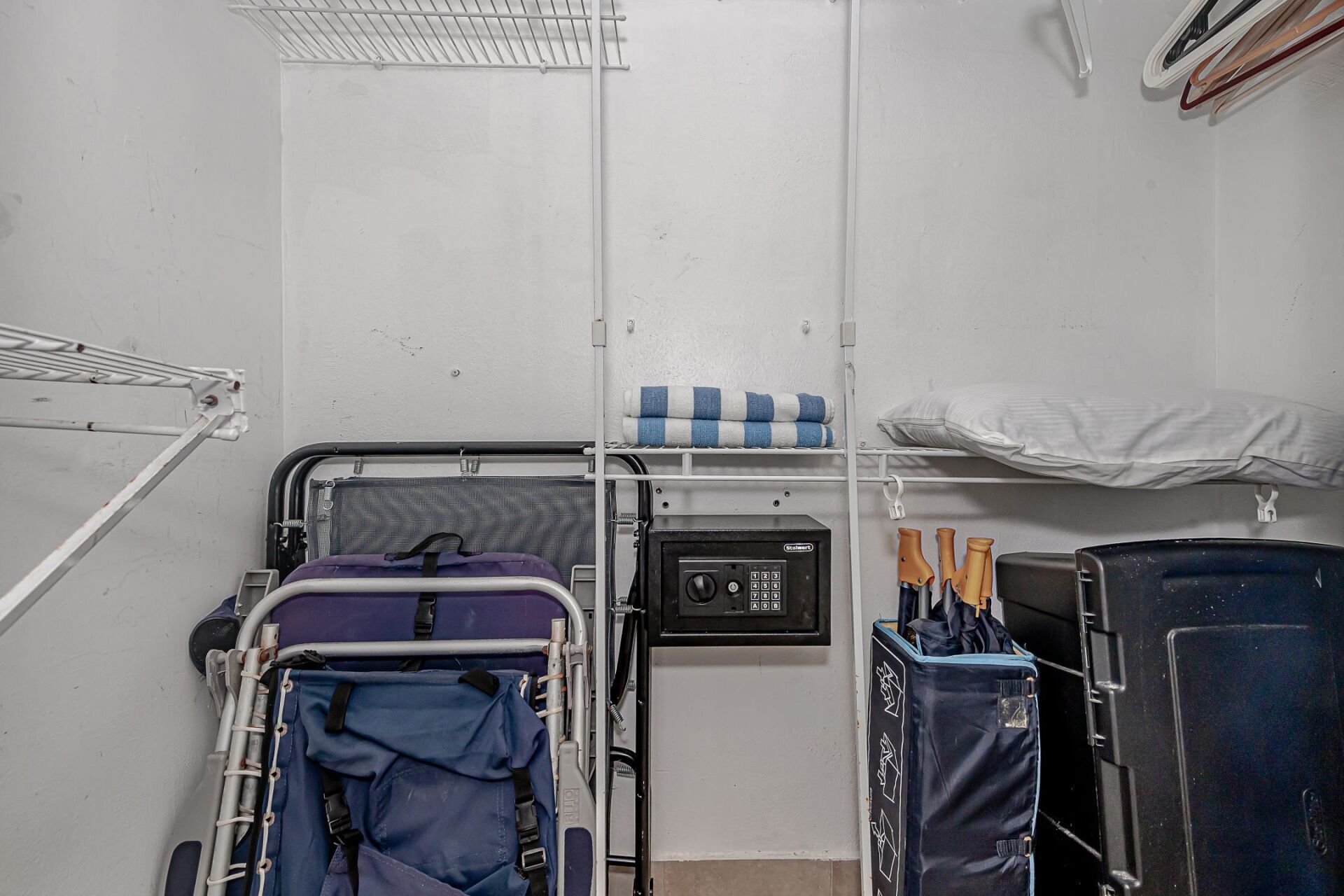A closet with a beach chair and umbrellas in it.