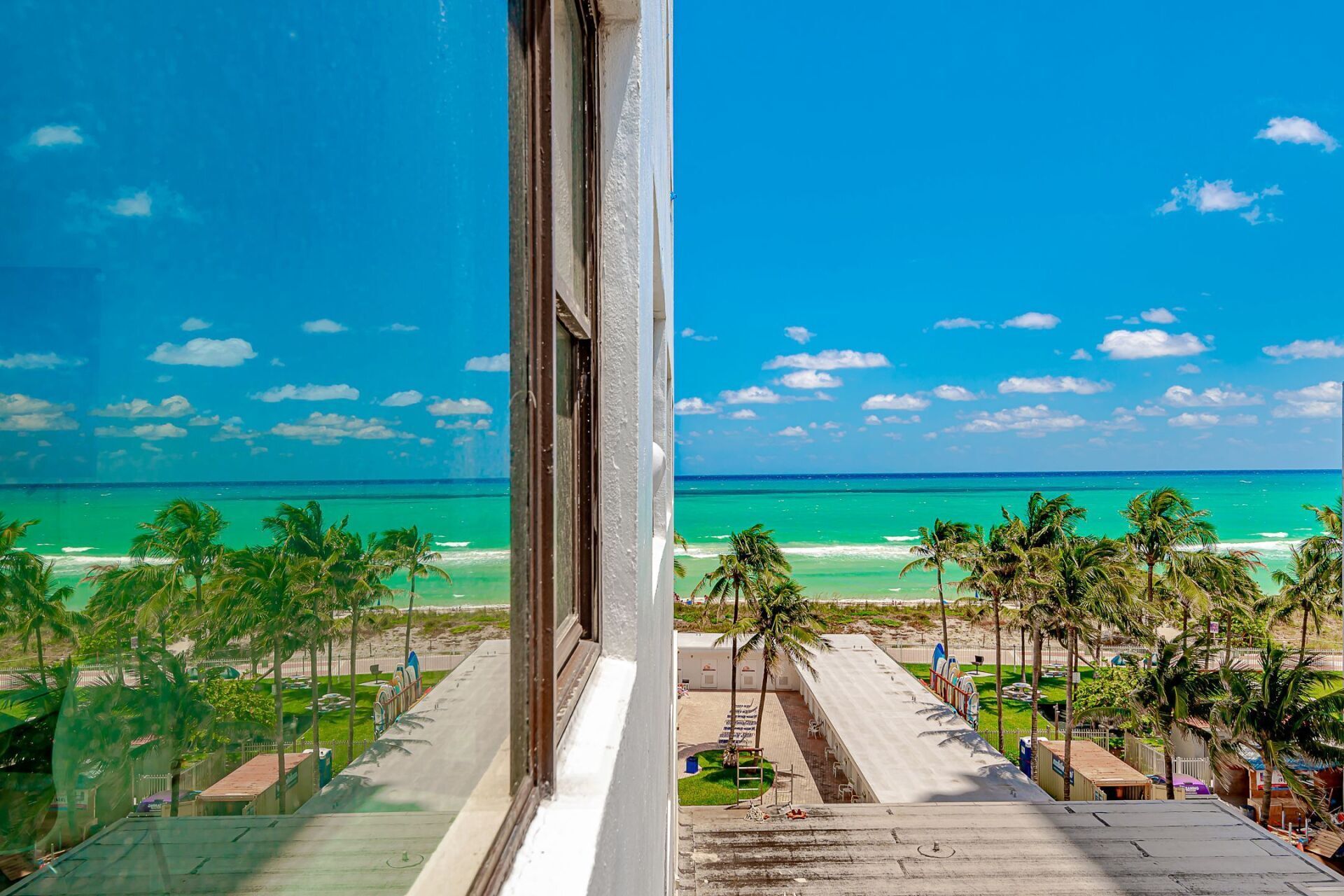 A window with a view of the ocean and palm trees