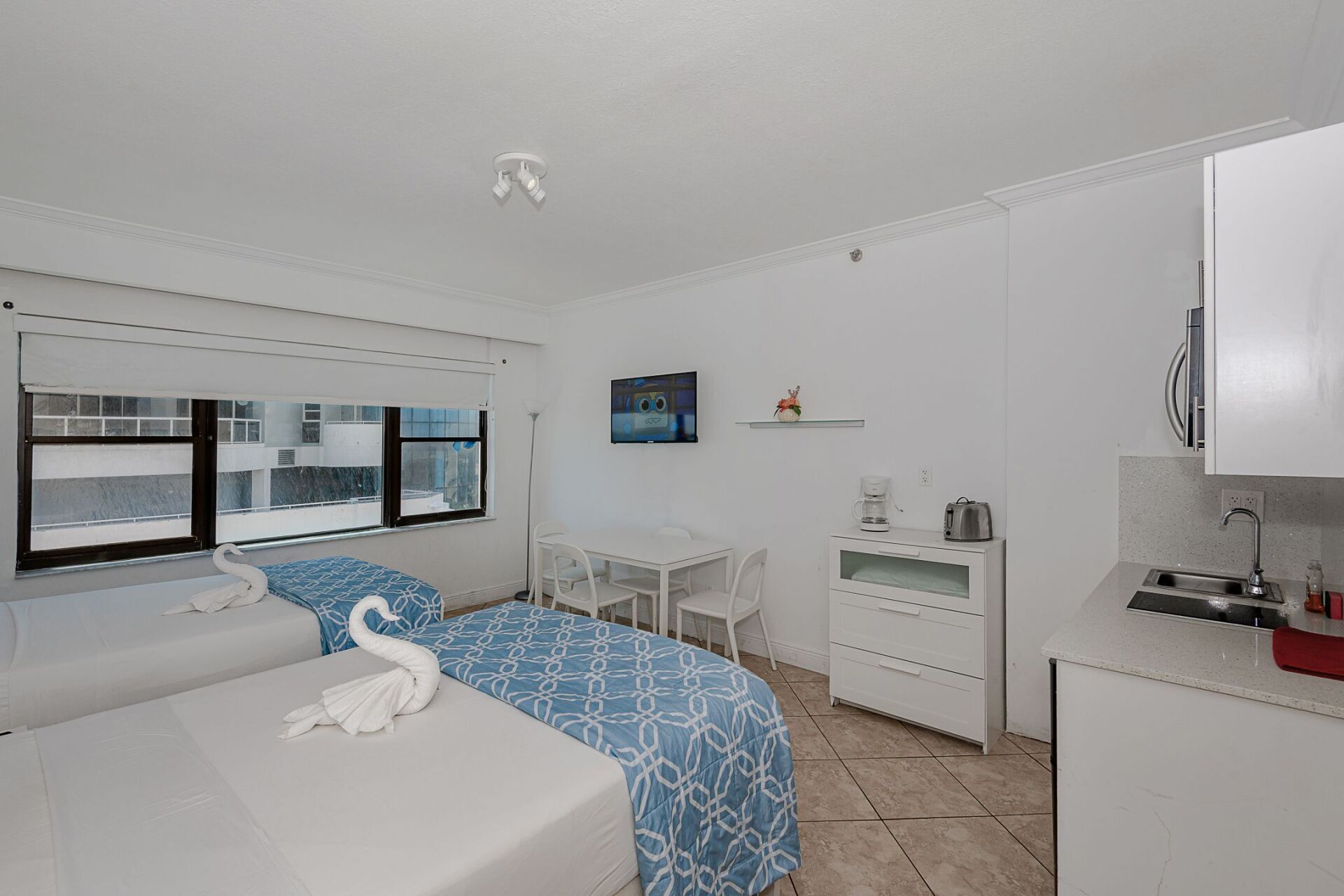 A hotel room with two beds , a table and a television.
