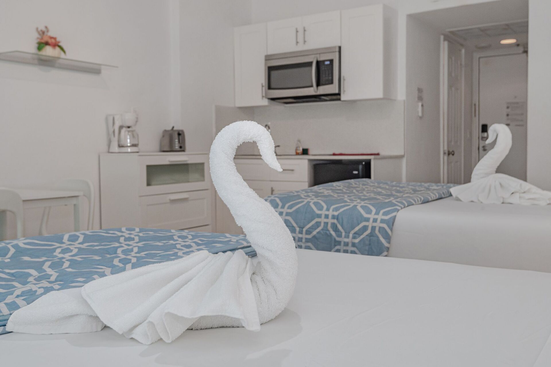 Two swans made out of towels are on a bed in a hotel room.