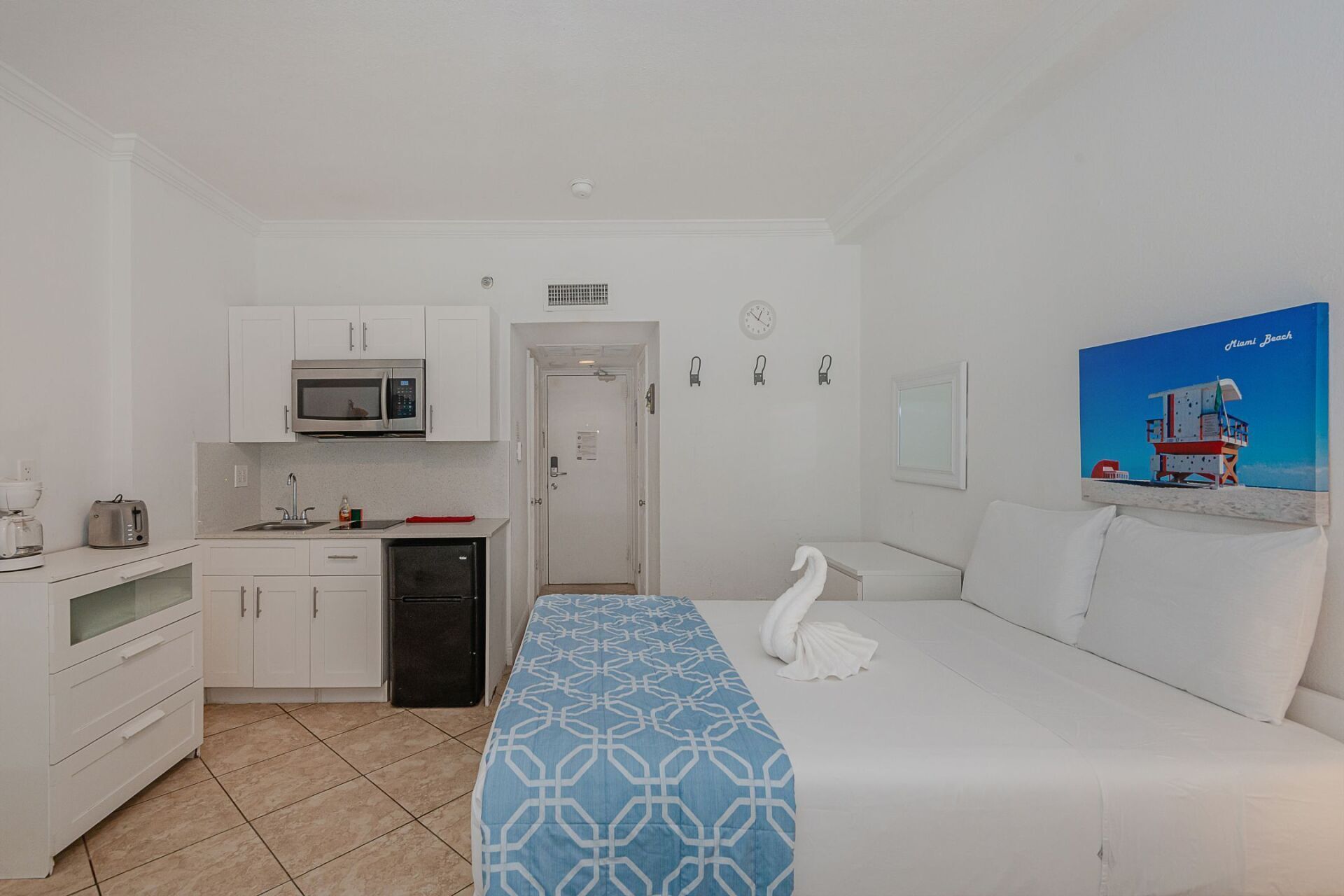 A hotel room with a bed , couch , kitchen and microwave.