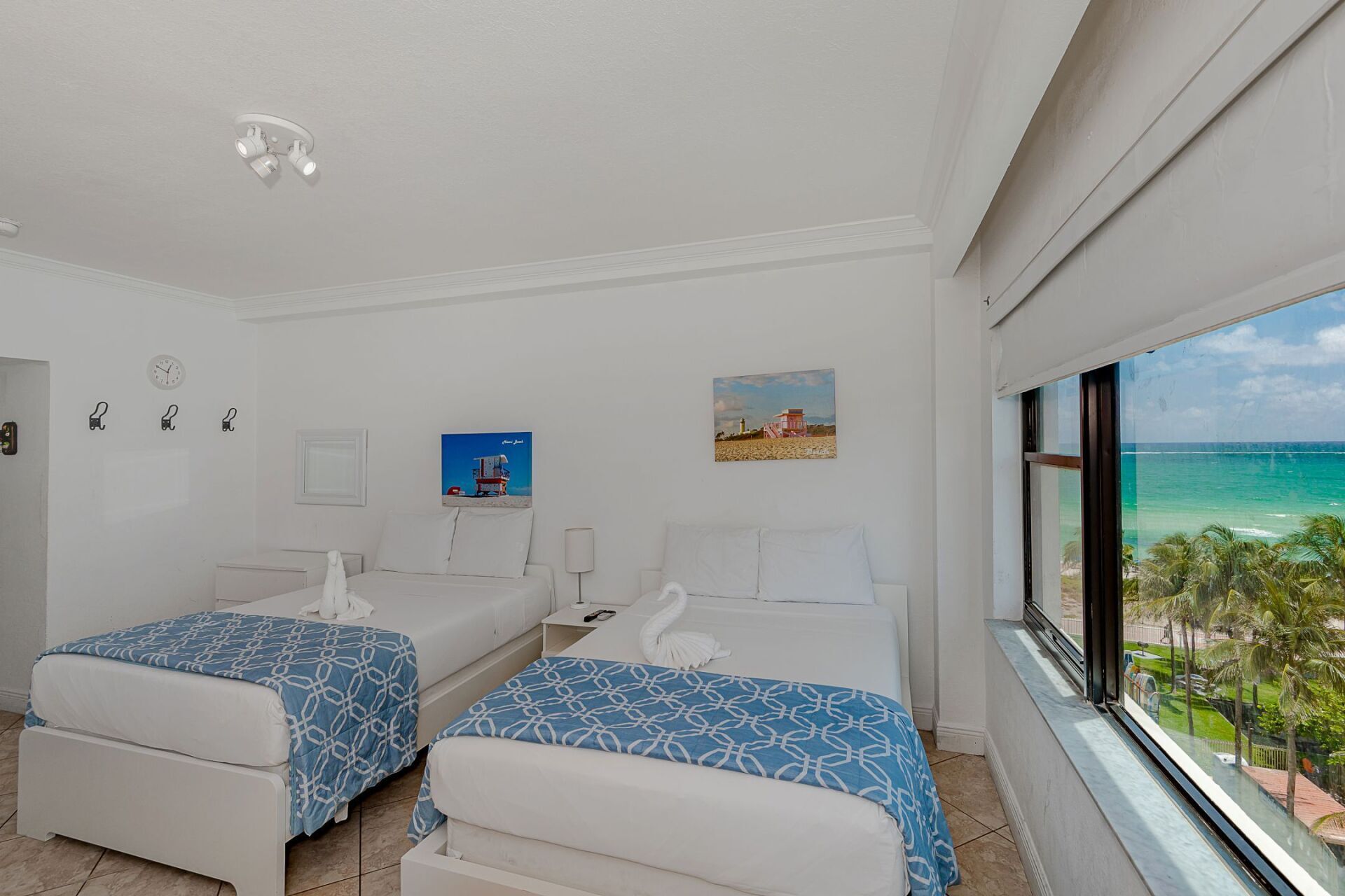 A hotel room with two beds and a large window overlooking the ocean.