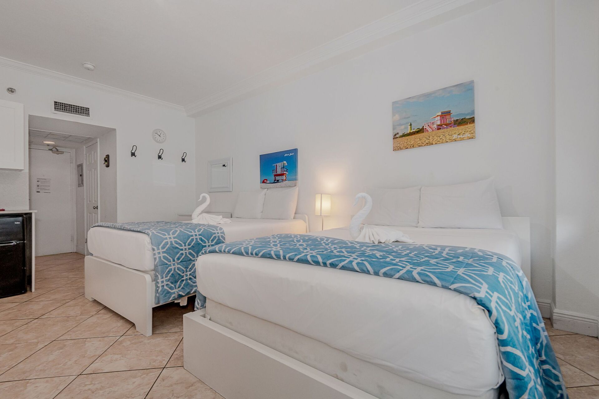 A bedroom with two beds and a painting on the wall.